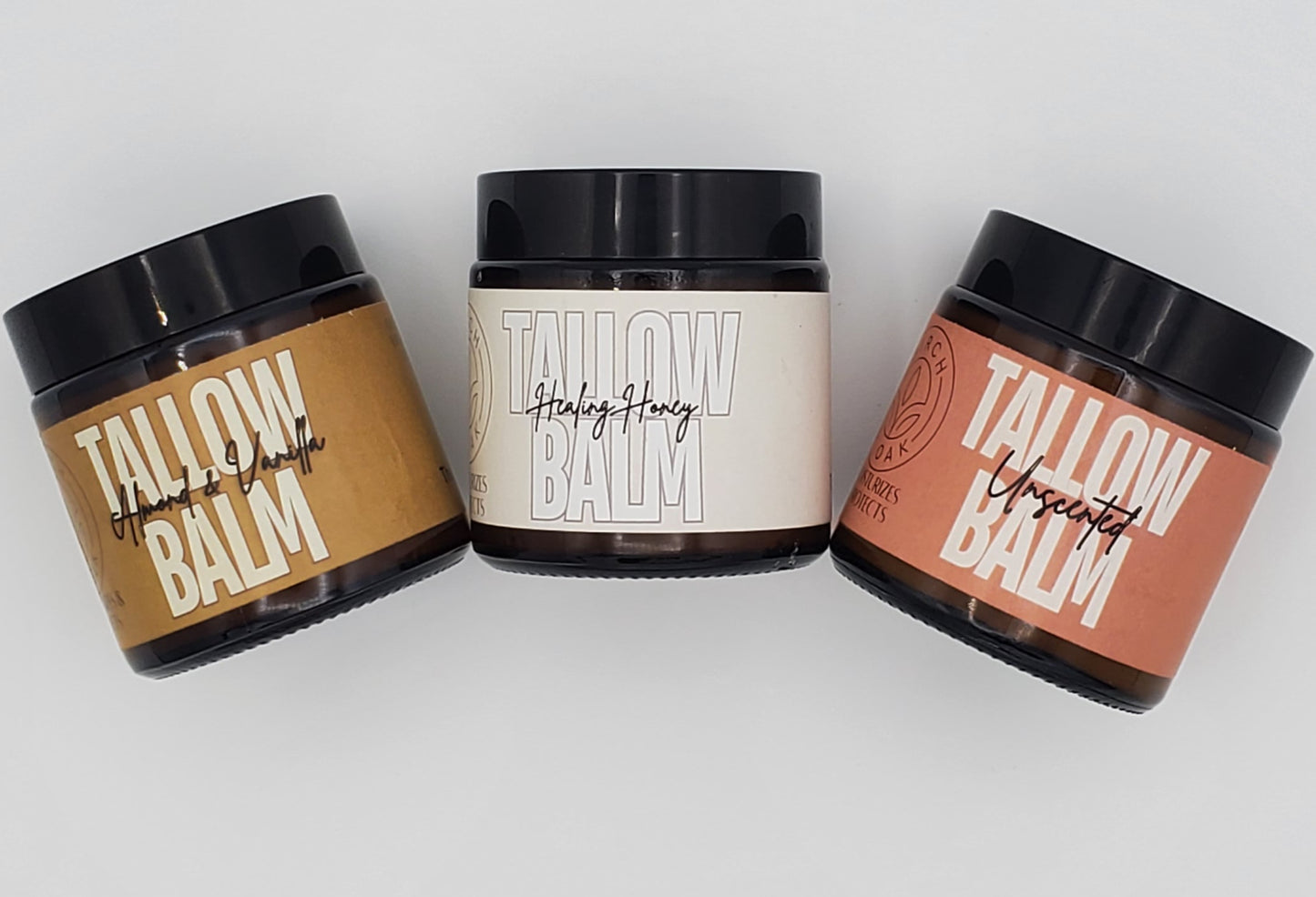 Three jars of Tallow Balm cream in different colors (beige, white, and brown) with simple, clean labels.