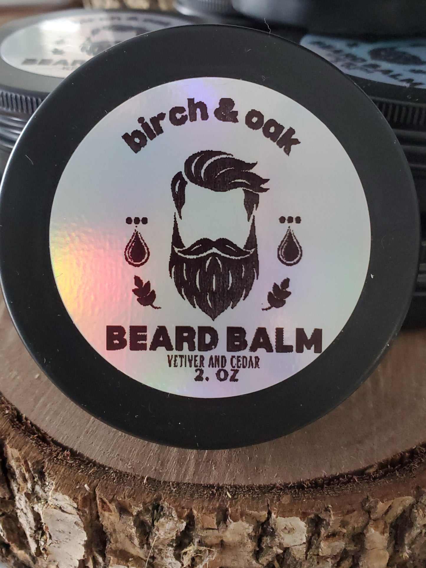 A container of Birch & Oak Beard Balm with the brand's logo and the words 'BEARD BALM VETIVER & CEDAR 2 oz' displayed on the lid.