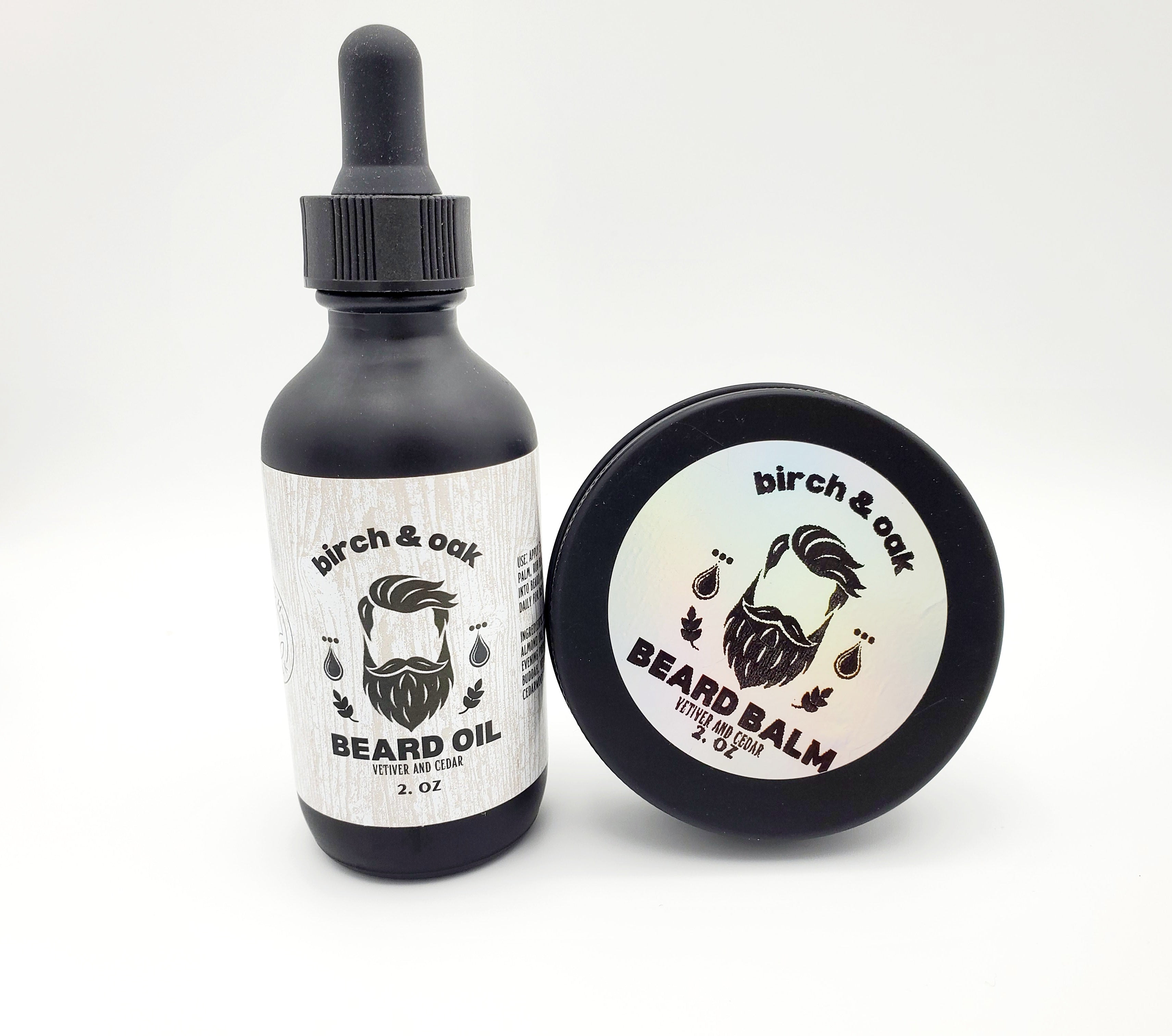 A bottle of Birch & Oak Beard Oil and a container of Beard Balm, both with white labels featuring a mustache and the names of the products.